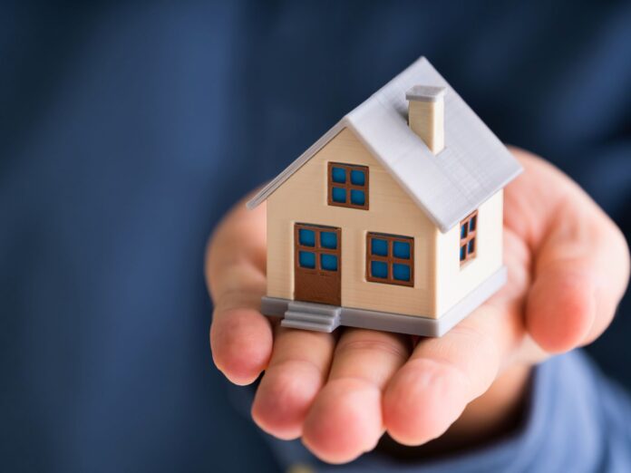 Due mani tengono il modellino di una casa