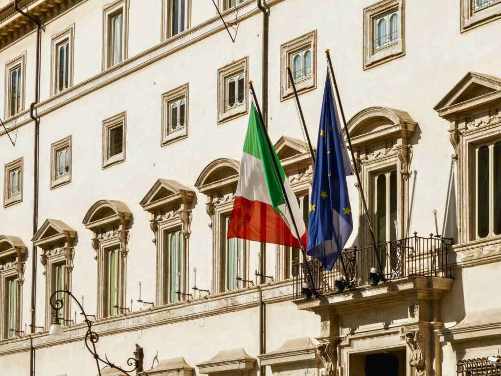 La bandiera italiana e quella UE sulla facciata di Palazzo Chigi a Roma